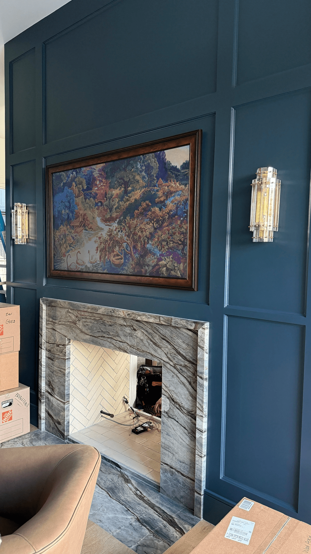 Wall sconces placed around a fireplace and artwork to complement the interior.